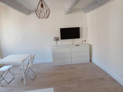 un salon blanc avec une table et une télévision dans l'établissement BudgetBnb 134, Toulon grand studio ensoleillé, à Toulon