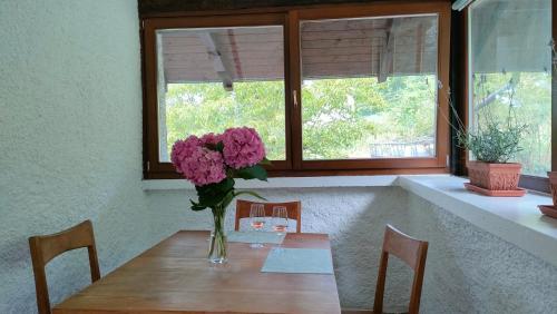 einen Tisch mit einer Vase lila Blumen drauf in der Unterkunft Agritur Cantina Romanese in Levico Terme
