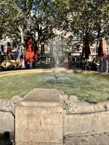 une fontaine dans un parc avec une femme en robe rouge dans l'établissement Beauregard home, à Dijon