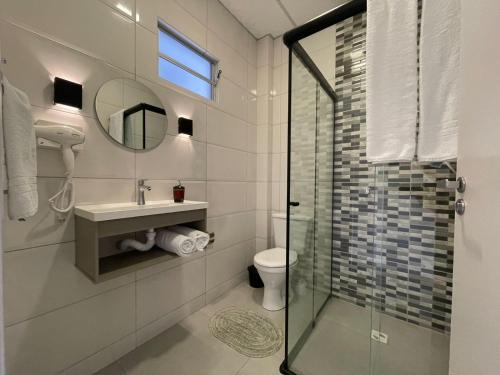 uma casa de banho com uma cabina de duche em vidro e um WC. em VILLA BILAC 03 - Studio próximo à Vila Germânica em Blumenau