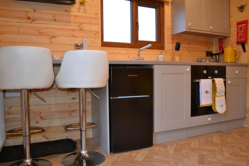 a kitchen with two bar stools and a sink at The Hive Lodge Cabin at Ashes Farm, near Settle in Settle