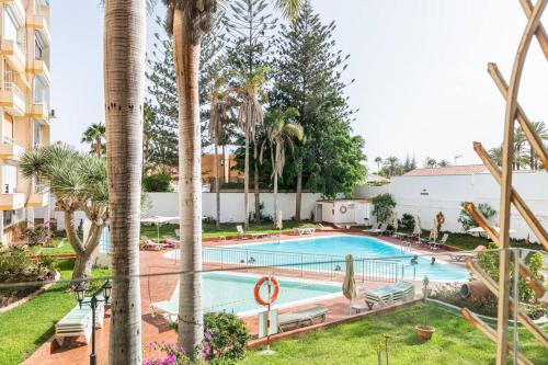 una piscina con palmeras y un edificio en Apartamento de lujo - Zona Yumbo - Playa del Ingles en San Bartolomé