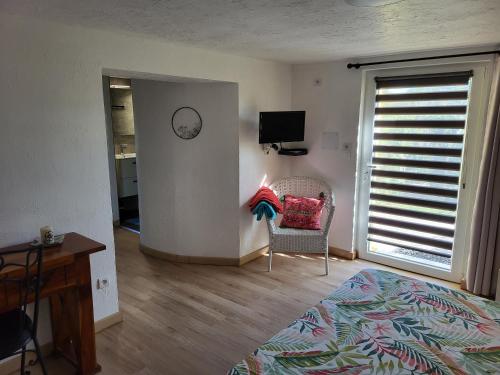 a bedroom with a bed and a chair and a window at Le Clos d'Auré. in Oberhaslach