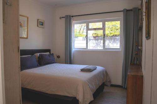 een slaapkamer met een groot bed en een raam bij Nirvana Cottage in Kaapstad