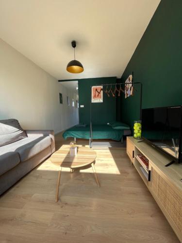 a living room with a bed and a coffee table at Le Roland-Garros in Chalon-sur-Saône