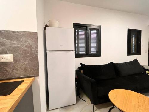 uma cozinha com um sofá preto e um frigorífico branco em LEGOS APARTMENTS em Tel Aviv