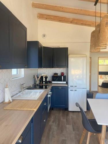 La cuisine est équipée de placards bleus et d'un réfrigérateur blanc. dans l'établissement Petite maison avec terrasse., à Ajaccio