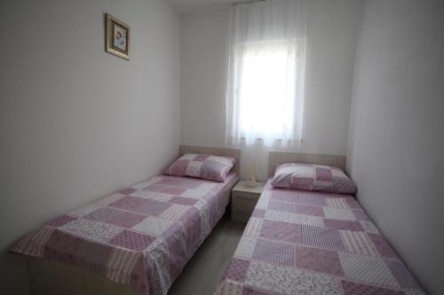 2 letti in una piccola camera con finestra di Apartments Villa Vetma a Kaštela (Castelli)