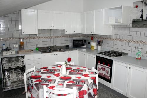 a white kitchen with a table with red and white chairs at Fior di Loto Apartment in Villar Focchiardo