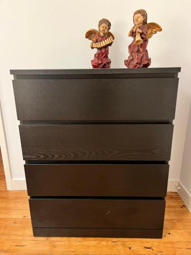 a black dresser with angel figurines on top of it at Casa das Memórias in Moita
