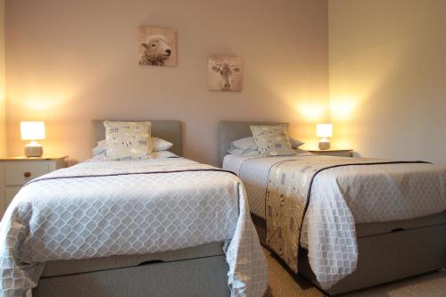 1 dormitorio con 2 camas y edredón blanco en Moo Cow Cottage Self Catering, en Oakham