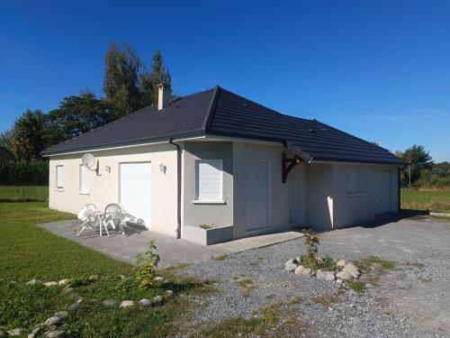 a small white garage with two chairs in front of it at Jolie villa 20min de Lourdes in Asson