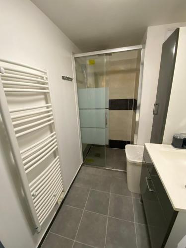 Un baño con ducha y puerta de cristal. en Haut Standing Suresnes, en Suresnes