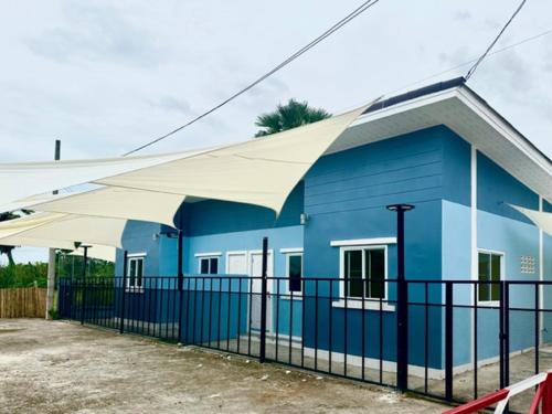 a blue building with a white canopy in front of it at กรชวัล วิลล่า in Nakhon Pathom