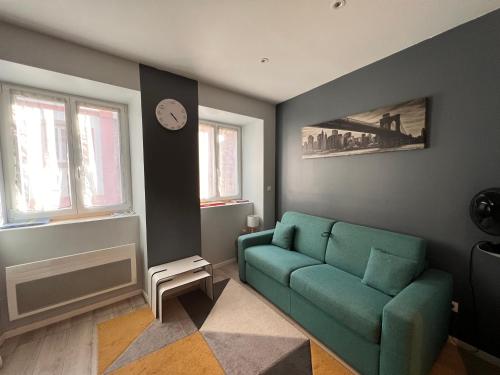 a living room with a green couch and a clock at Studio tout confort 2 personnes au coeur de l'Alsace in Wolxheim