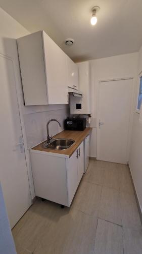 uma cozinha com armários brancos, um lavatório e uma porta em T2 Proximité La Défense em Colombes