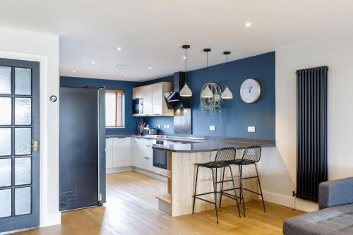 cocina con paredes azules y 2 taburetes en Stylish & modern 4-bedroom home with sea views, en Brighton & Hove
