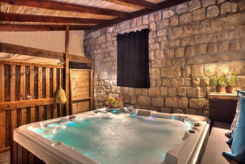 a large bath tub in a room with a stone wall at אבני החושן - סוויטות יוקרה בצפת העתיקה - Avnei Hachoshen - Luxury Suites in the Old City in Safed