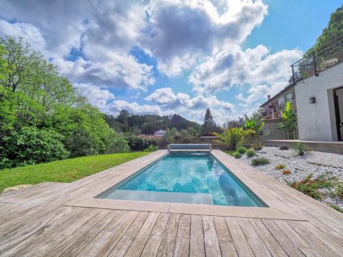 a swimming pool in a yard with a wooden deck at VILLA MADHUKA - Chambres d'hôtes in Hendaye