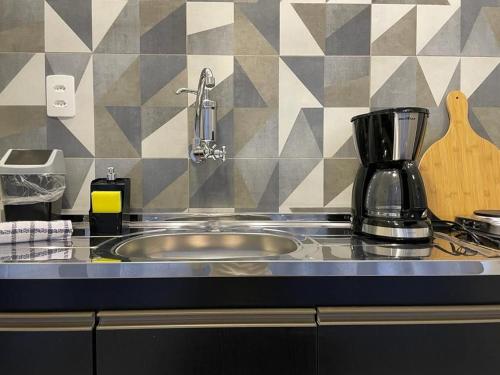 a kitchen counter with a sink and a coffee maker at VILLA BILAC 01 - Studio próximo à Vila Germânica in Blumenau