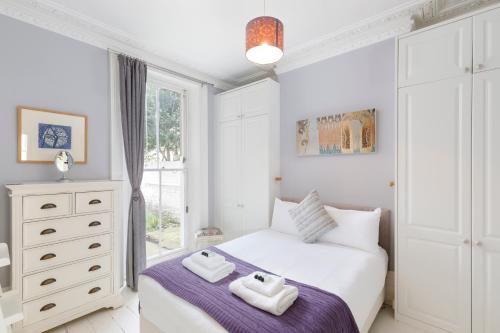 a white bedroom with a bed and a window at Hove garden flat, pet friendly in Brighton & Hove
