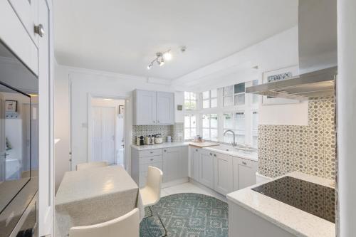 a white kitchen with white cabinets and a table at Hove garden flat, pet friendly in Brighton & Hove