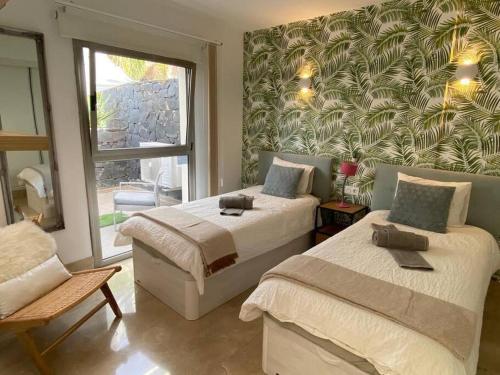 ein Schlafzimmer mit zwei Betten und einem großen Fenster in der Unterkunft Amazing Luxury Seafront Villa near Golf & Ocean in San Miguel de Abona
