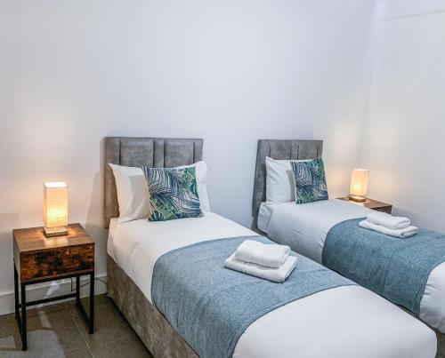 2 camas individuales en una habitación con 2 lámparas en Swindon City Centre Apartments by Elegance Living, en Swindon