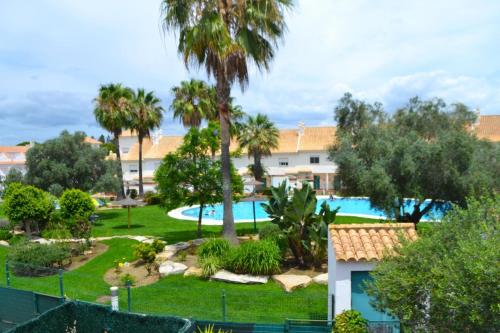 a resort with a swimming pool and palm trees at Adosado de lujo en El Portil Playa y Golf in El Portil