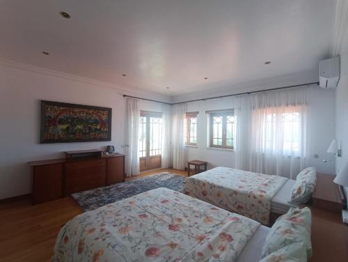 a bedroom with two beds and a table and windows at Casa Grande in Golpilheira