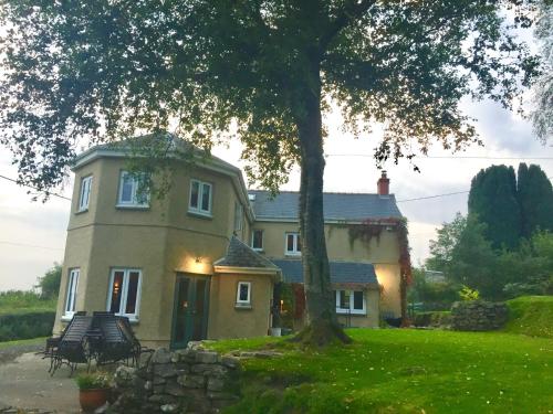 une grande maison avec un arbre en face dans l'établissement Efail Y Garn, à Swansea