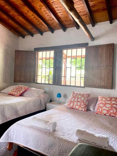 two beds in a room with two windows at Villa tolu in San Gil