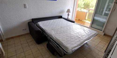 - un lit dans une chambre à côté d'une fenêtre dans l'établissement Appartement T2 + cabine - classé 3 étoiles, à Bormes-les-Mimosas