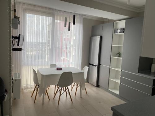 a kitchen with a white table and chairs and a refrigerator at Zoe’s cozy apartment in Chişinău