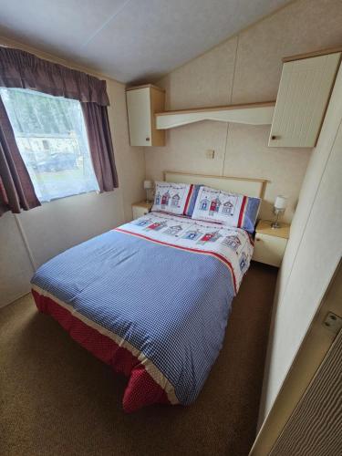 a small bedroom with a bed with a blue blanket at Liberty Caravan Hire in Chapel Saint Leonards