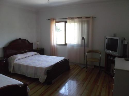 a bedroom with a bed and a television and a window at Albergue Constantino AL in Paredes de Coura