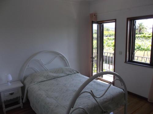 a bedroom with a white bed and a balcony at Albergue Constantino AL in Paredes de Coura