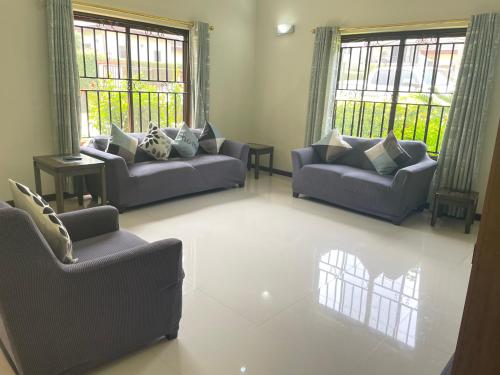 a living room with two couches and two windows at Aspen Luxury Villa in Accra
