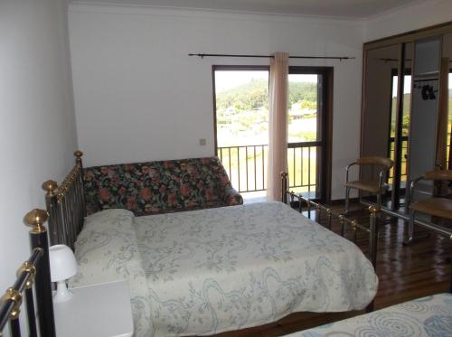 a bedroom with a bed and a balcony at Albergue Constantino AL in Paredes de Coura