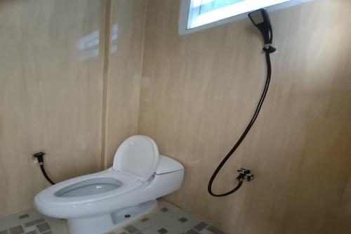 a bathroom with a white toilet and a window at OYO 93126 Nrc White House in Duri