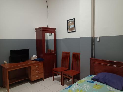 a bedroom with a bed and a desk and a computer at OYO 93117 Penginapan Tiga Dara in Jayapura