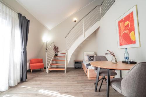 a living room with a staircase and a table and chairs at Hotel CityHome am Kurpark in Bad Salzuflen