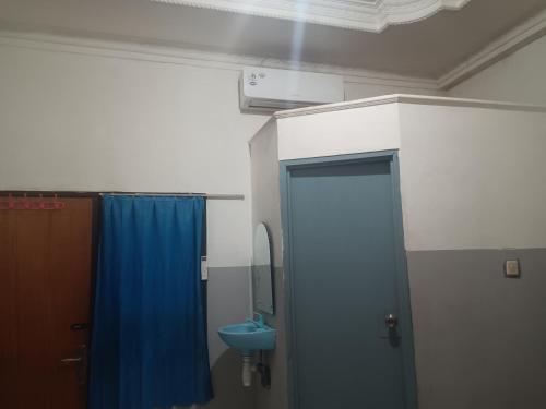 a bathroom with a blue shower curtain and a toilet at OYO 93090 Multi Plus Inn in Jayapura