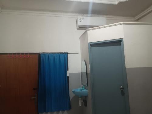 a bathroom with a blue shower curtain and a sink at OYO 93090 Multi Plus Inn in Jayapura