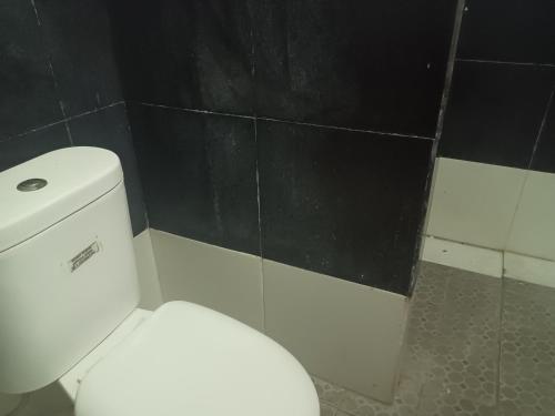 a white toilet in a bathroom with a black wall at OYO 93090 Multi Plus Inn in Jayapura