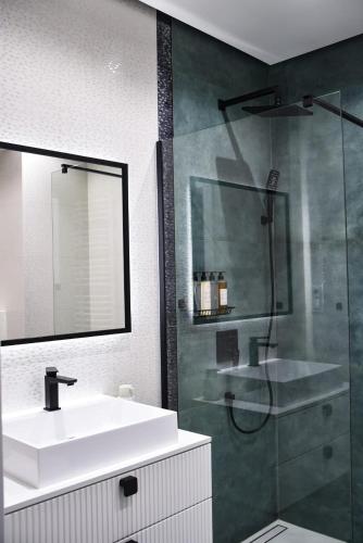 a bathroom with a sink and a glass shower at Benefis Tatarska in Przemyśl