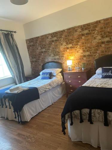 a bedroom with two beds and a brick wall at The Gables 