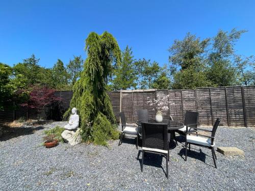 a patio with a table and chairs and a tree at The Gables 