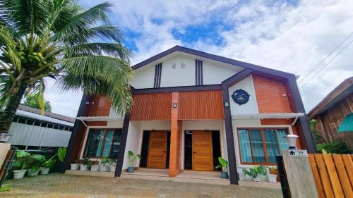 a house with a palm tree in front of it at มาเหนือพูลวิลล่า แม่แจ่ม เชียงใหม่ Ma-Nhuer pool villa Mae Chaem Chiangmai 