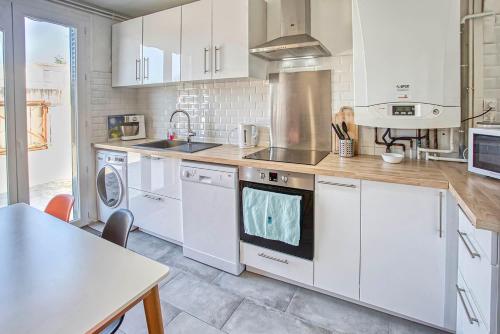 a kitchen with white cabinets and a sink and a table at Le Havre Chic et Spacieux d'Angoulême - Calme & Confort Moderne in Angoulême